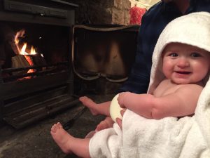 Emily warming her toes by the fire in Hollies Cottage, Somerset