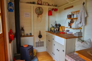 The kitchen with log burner inside the shepherd's hut at Warmwell House.