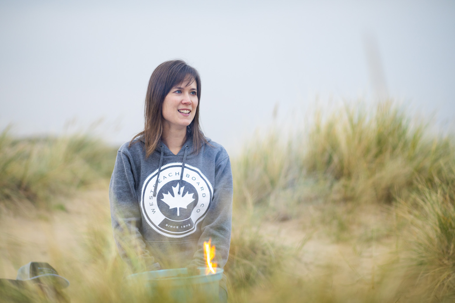 An image of myself sat in the sand dunes at Camber Sands wearing a grey hoodie from West Beach