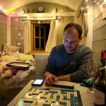 Matt playing scrabble in the shepherd's hut, Warmwell, Dorset