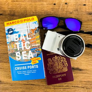 A flat lay image of my travel must haves: Baltic Sea Ports Marco Polo Travel Guide, sunglasses and camera