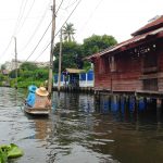 Unique views of Bangkok on the Chao Phraya River. Two ladies in a boat and houses on stilts